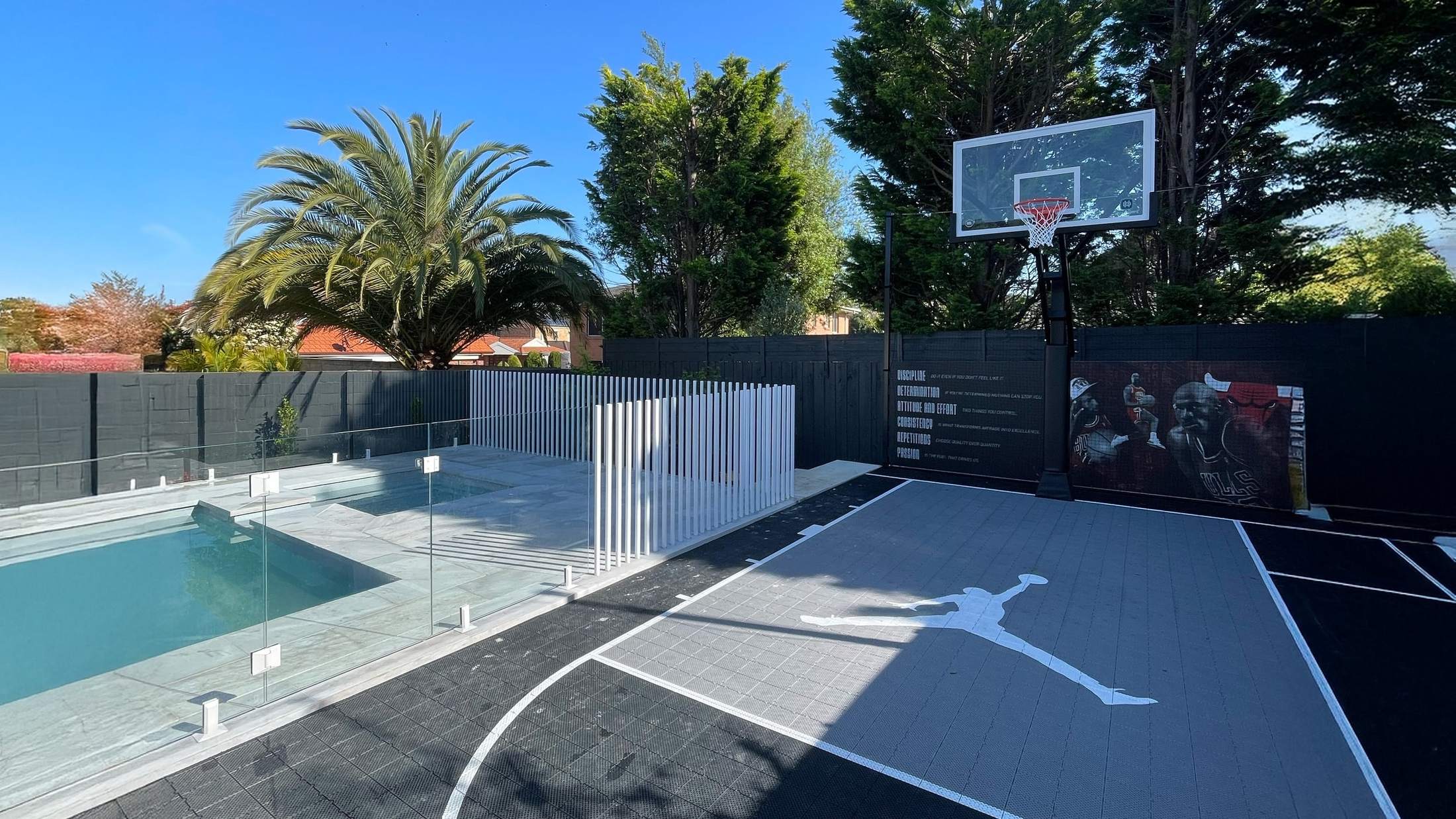 Glass pool fence beside a pool and basketball court