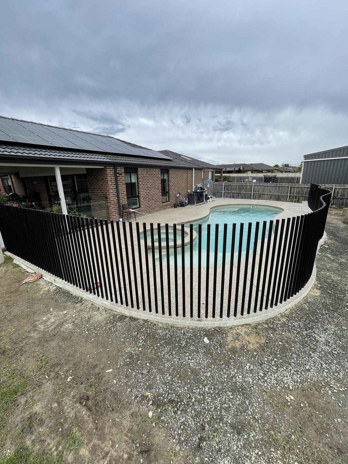 Curved black steel rod pool fence on a new build