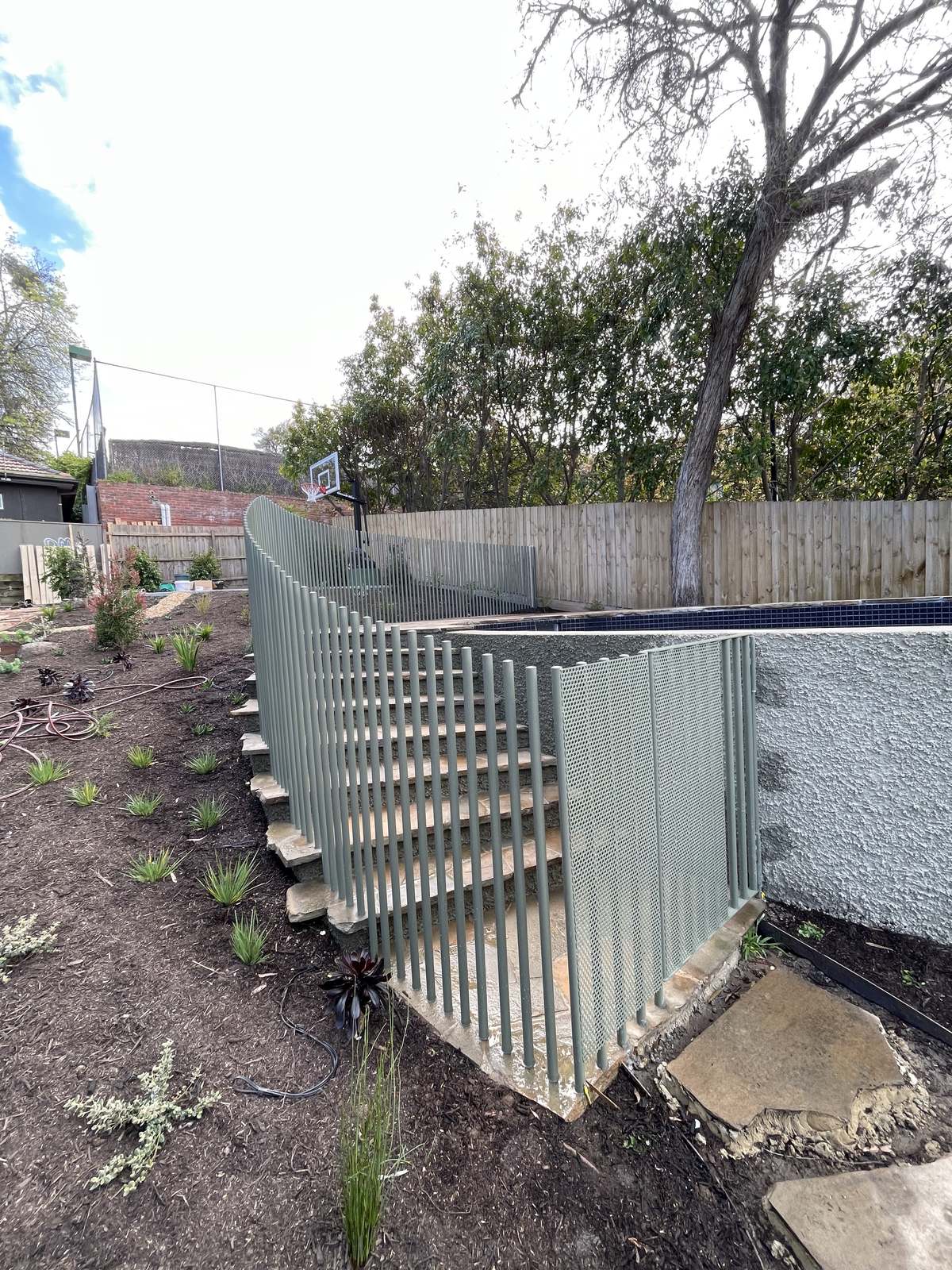 Aluminium rod pool fence stepping down a sloping site