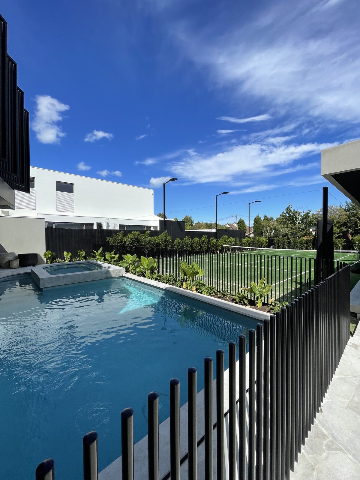 Black aluminium rod pool fence beside a blue pool